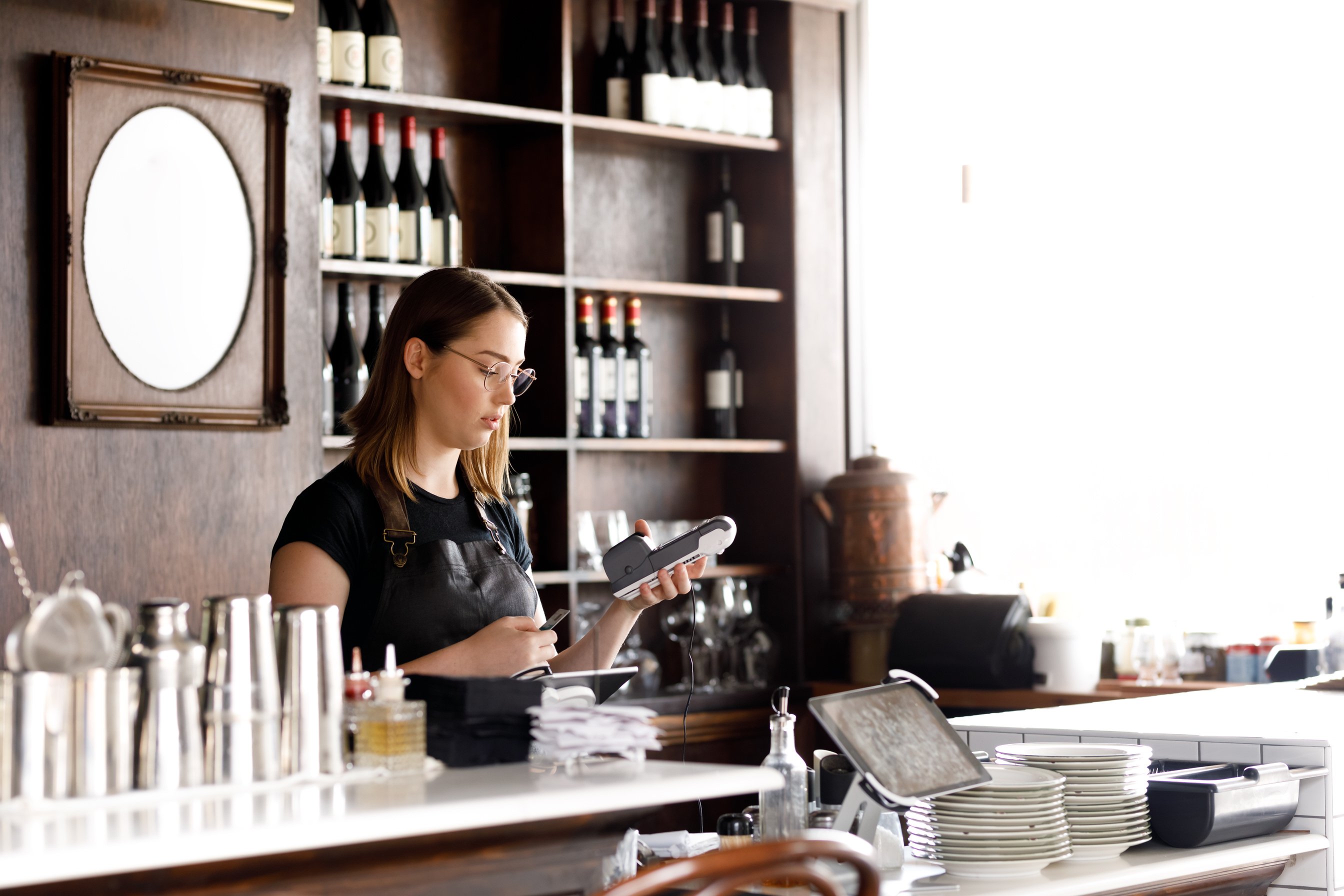 Female Cafe Worker Accepting Payment With Contactless POS machine